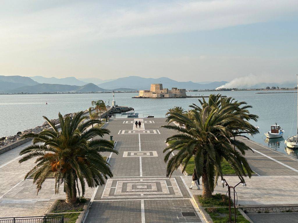 Promenade in Nafplio mit Palmen und Blick auf die Bourtzi Festung im Hafen von Griechenland