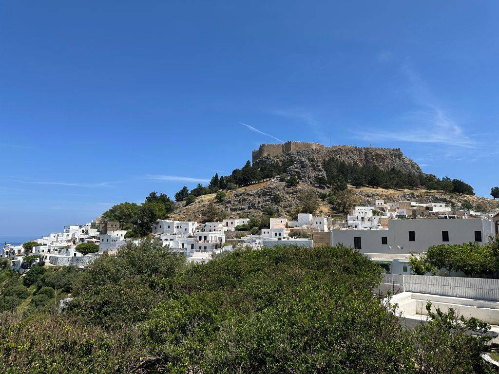 Panoramablick auf Lindos mit der berühmten Akropolis von Lindos, weißen Häusern und der Küstenlandschaft der Insel Rhodos.