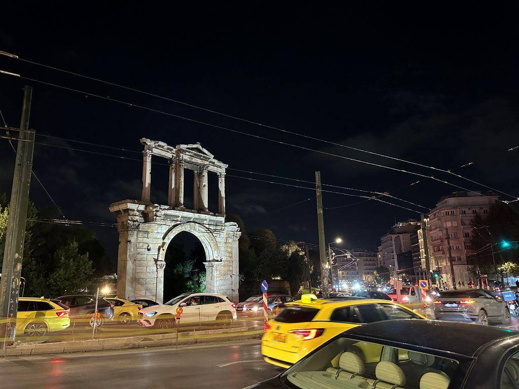 Hadrianstor in Athen bei Nacht mit beleuchtetem antiken Torbogen und Verkehr auf der Straße in Griechenland