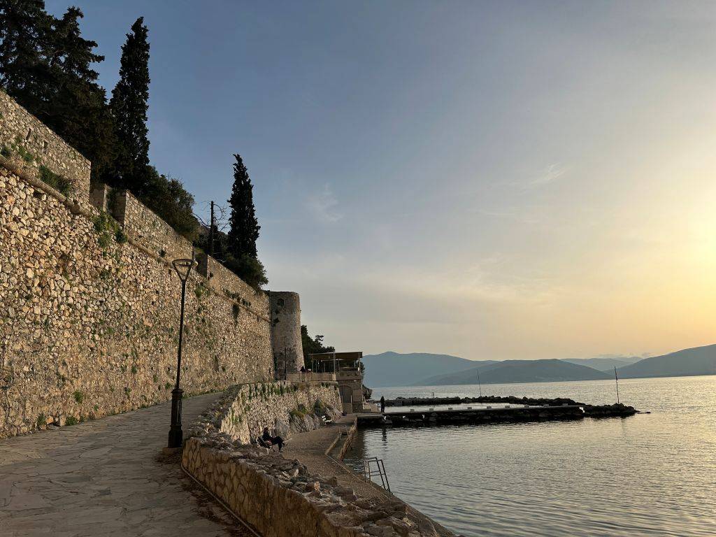Westliche Promenade von Nafplio nahe Omilos Bar Restaurant bei Sonnenuntergang mit Blick auf das Meer und die Berge in Griechenland